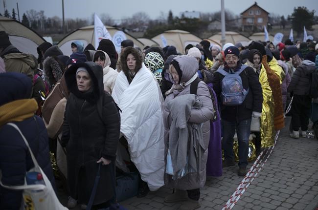 Refugees wait in a crowd for transportation after fleeing from the Ukraine and arriving at the border crossing in Medyka, Poland, Monday, March 7, 2022. Hundreds of thousands of Ukrainian civilians attempting to flee to safety Sunday were forced to shelter from Russian shelling that pummeled cities in Ukraine’s center, north and south. (AP Photo/Markus Schreiber)