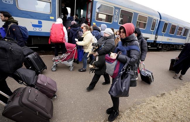 Two people hold on to their pets, after fleeing from Ukraine, as they run for a train to Budapest at the station in Zahony, Hungary, Monday, March 7, 2022. Russia's invasion of Ukraine has set off the largest mass migration in Europe in decades, with more than 1.5 million people having crossed from Ukraine into neighboring countries. (AP Photo/Darko Vojinovic)