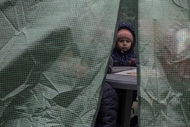 Refugees warm up inside a plastic tent after fleeing from the Ukraine and arriving at the border crossing in Medyka, Poland, Monday, March 7, 2022. Russia announced yet another cease-fire and a handful of humanitarian corridors to allow civilians to flee Ukraine. Previous such measures have fallen apart and Moscow’s armed forces continued to pummel some Ukrainian cities with rockets Monday. (AP Photo/Visar Kryeziu)