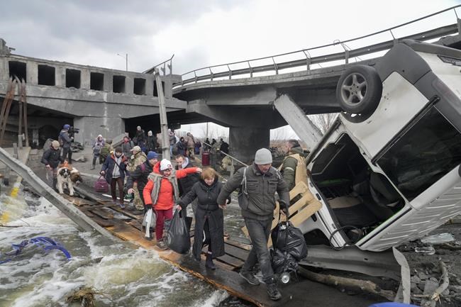 People cross an improvised path under a destroyed bridge while fleeing the town of Irpin close to Kyiv, Ukraine, Monday, March 7, 2022.Russia announced yet another cease-fire and a handful of humanitarian corridors to allow civilians to flee Ukraine. Previous such measures have fallen apart and Moscow’s armed forces continued to pummel some Ukrainian cities with rockets Monday. (AP Photo/Efrem Lukatsky)