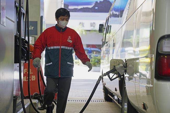 A staff member fills up a van with gasoline at a gas station in Hong Kong, Tuesday, March 8, 2022. (AP Photo/Kin Cheung)