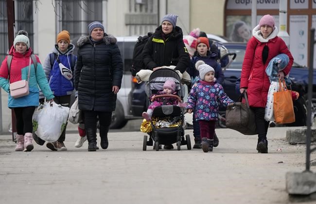 Women and children, fleeing from Ukraine, arrive on the platform of the train station in Przemysl, Poland, after disembarking from a bus which traveled from the border, Tuesday, March 8, 2022. Russia's invasion of Ukraine has set off the largest mass migration in Europe in decades, with more than 1.5 million people having crossed from Ukraine into neighboring countries. (AP Photo/Markus Schreiber)