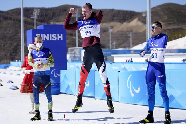 Canada's Mark Arendz, center, jumps during a ceremony for the men's middle distance standing event at the 2022 Winter Paralympics, Tuesday, March 8, 2022, in Zhangjiakou, China. Arendz won the gold, Grygorii Vovchynskyi, left, of Ukraine silver, and Alexandr Gerlits of Kazakshstan bronze. (AP Photo/Shuji Kajiyama)