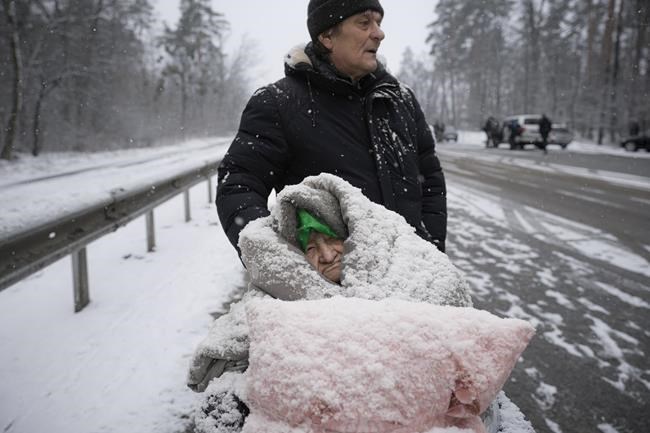 An elderly woman is coated in snow as she sits in a wheelchair after being evacuated from Irpin, on the outskirts of Kyiv, Ukraine, Tuesday, March 8, 2022. Demands for ways to safety evacuate civilians have surged along with intensifying shelling by Russian forces, who have made significant advances in southern Ukraine but stalled in some other regions. Efforts to put in place cease-fires along humanitarian corridors have repeatedly failed amid Russian shelling. (AP Photo/Vadim Ghirda)