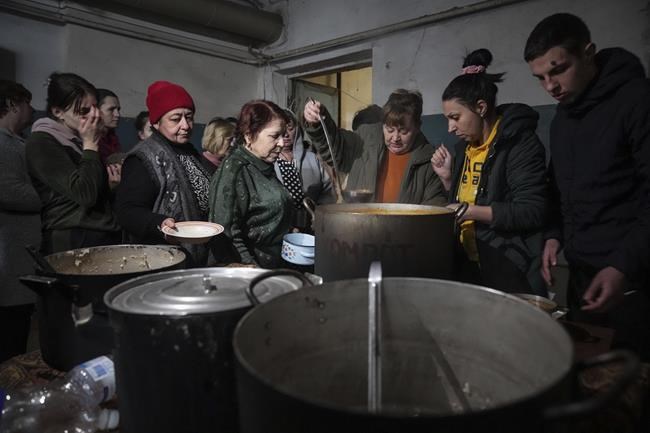 People queue to receive hot food in the improvised bomb shelter in Mariupol, Ukraine, Monday, March 7, 2022. (AP Photo/Evgeniy Maloletka)