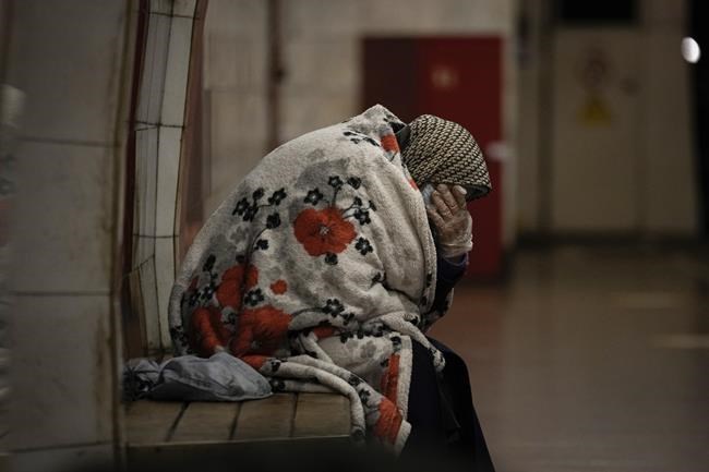 An elderly woman sits on a bench wrapped in a blanket in a subway station turned into a shelter in Kyiv, Ukraine, Tuesday, March 8, 2022. (AP Photo/Vadim Ghirda)
