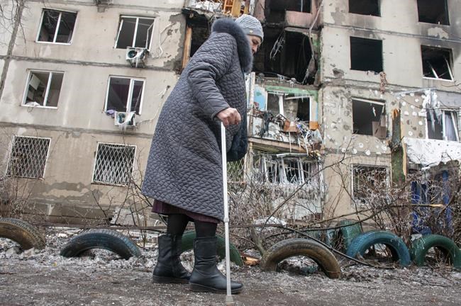 A woman walks past an apartment building hit by shelling in Kharkiv, Ukraine, Tuesday, March 8, 2022. (AP Photo/Andrew Marienko)