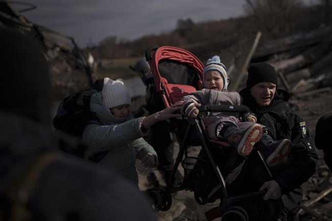 A child is carried on a stroller across an improvised path while fleeing Irpin, on the outskirts of Kyiv, Ukraine, Wednesday, March 9, 2022. (AP Photo/Felipe Dana)