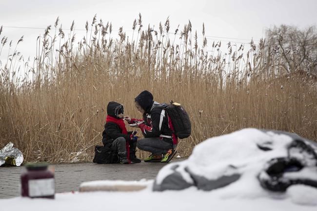 Tatiana Kostyuk, 38, from Zaporozhye, gives food to a child after fleeing Ukraine, at the border crossing in Medyka, Poland, Wednesday, March 9, 2022. U.N. officials said that the Russian onslaught has forced 2 million people to flee Ukraine. It has trapped others inside besieged cities that are running low on food, water and medicine amid the biggest ground war in Europe since World War II. (AP Photo/Visar Kryeziu)