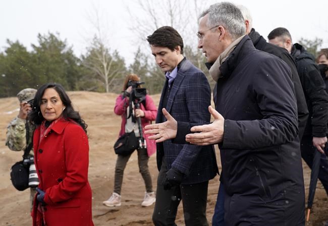 The head of the NATO military alliance says he welcomes Prime Minister Justin Trudeau's assertion that Canada will be looking at increasing its military spending following Russia's invasion of Ukraine. NATO Secretary General Jens Stoltenberg, right, Canadian Prime Minister Justin Trudeau, center, and Canadian Minister of National Defense Anita Anand talk to each other during their visit to Adazi Military base in Kadaga, Latvia, Tuesday, March. 8, 2022. (AP Photo/Roman Koksarov)
