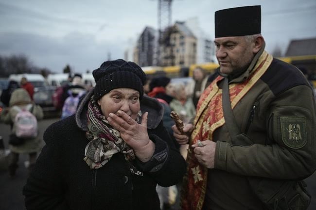 A military priest tries to comfort a crying woman who was evacuated from Irpin, at a triage point in Kyiv, Ukraine, Wednesday, March 9, 2022. (AP Photo/Vadim Ghirda)