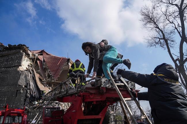 Firefighters help a woman to evacuate from a damaged by shelling apartment building in Mariupol, Ukraine, Thursday, March 10, 2022. (AP Photo/Evgeniy Maloletka)