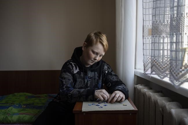 Tymur Samolevska, 12, a Ukrainian internally displaced from Zaporizhya, puts together a puzzle inside a dorm in Novoiavorisk, near Lviv, western Ukraine, Sunday, March 13, 2022. (AP Photo/Bernat Armangue)