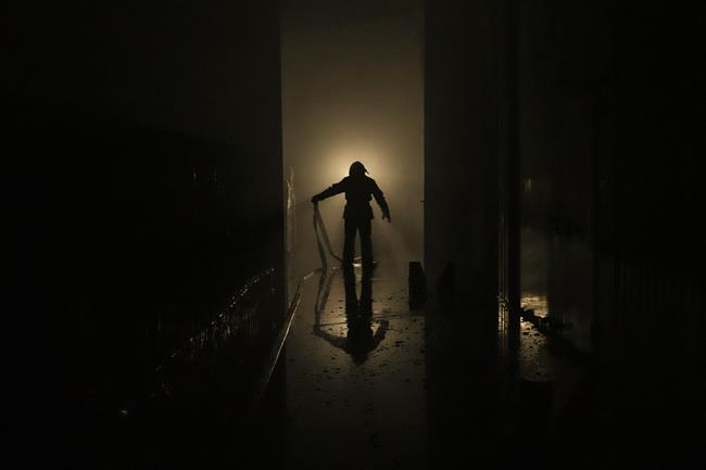 A Ukrainian firefighter drags a hose inside a large food products storage facility which was destroyed by an airstrike in the early morning hours in Brovary, north of Kyiv, Ukraine, Sunday, March 13, 2022. Waves of Russian missiles pounded a military training base close to Ukraine's western border with NATO member Poland, killing 35 people, following Russian threats to target foreign weapon shipments that are helping Ukrainian fighters defend their country against Russia's grinding invasion.(AP Photo/Vadim Ghirda)