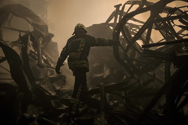 A Ukrainian firefighter walks inside a large food products storage facility which was destroyed by an airstrike in the early morning hours on the outskirts of Kyiv, Ukraine, Sunday, March 13, 2022. Waves of Russian missiles pounded a military training base close to Ukraine's western border with NATO member Poland, killing 35 people, following Russian threats to target foreign weapon shipments that are helping Ukrainian fighters defend their country against Russia's grinding invasion.(AP Photo/Vadim Ghirda)