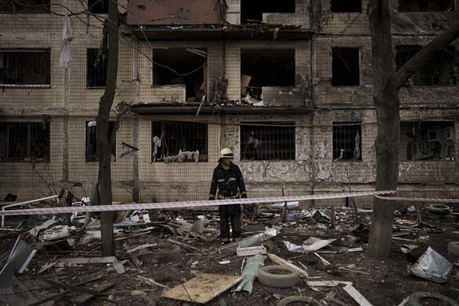 A Ukrainian firefighter walks outside a destroyed building after it was hit by artillery shelling in Kyiv in Kyiv, Ukraine, Monday, March 14, 2022. (AP Photo/Felipe Dana)