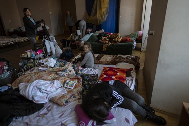 Families who fled the war in Ukraine stay inside a school in Przemysl, southeastern Poland, on Monday, March 14, 2022. Russia's military forces kept up their punishing campaign to capture Ukraine's capital with fighting and artillery fire in Kyiv's suburbs Monday after an airstrike on a military base near the Polish border brought the war dangerously close to NATO's doorstep. (AP Photo/Petros Giannakouris)