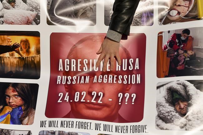 A woman touches a banner depicting Russian President, Vladimir Putin with the text