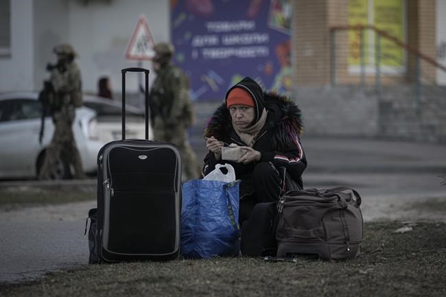 A refugee woman eats in Brovary, Ukraine, Sunday, March 20, 2022, after 1,600 people, of which half are children according to authorities, were evacuated from the village of Bobrik, reportedly under Russian military control. Russian forces pushed deeper into Ukraine's besieged and battered port city of Mariupol on Saturday, where heavy fighting shut down a major steel plant and local authorities pleaded for more Western help. (AP Photo/Vadim Ghirda)