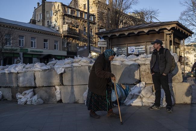 An elderly woman walks pass concrete blocks topped with sandbags at a street in Odesa, southern Ukraine, on Tuesday, March 22, 2022.(AP Photo/Petros Giannakouris)