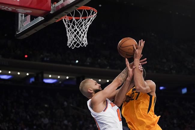 New York Knicks' Evan Fournier, left, fouls Utah Jazz's Rudy Gobert who was on his way to the basket during the second half of an NBA basketball game, Sunday, March 20, 2022, in New York. (AP Photo/Seth Wenig)