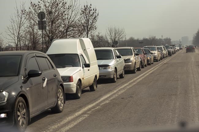 Local residents lineup in their cars to leave Mariupol for more peaceful place on the territory which is under the Government of the Donetsk People's Republic control, on the outskirts of Mariupol, Ukraine, Thursday, March 24, 2022. (AP Photo/Alexei Alexandrov)