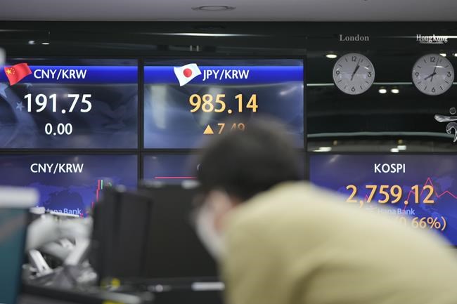 A currency trader watches computer monitors near screens showing the Korea Composite Stock Price Index (KOSPI), right, and the foreign exchange rates at a foreign exchange dealing room in Seoul, South Korea, Wednesday, March 30, 2022. Asian stock markets followed Wall Street higher on Wednesday as talks on ending Russia's war on Ukraine appeared to make progress. (AP Photo/Lee Jin-man)