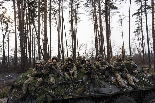 Ukrainian soldiers pass on top of an armored vehicle in the outskirts of Kyiv, Ukraine, Thursday, March 31, 2022. (AP Photo/Rodrigo Abd)