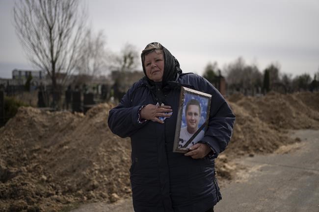 A woman carries the portrait of Dmytro Stefienko, 32, a civilian killed during the war with Russia, during his funeral in Bucha, in the outskirts of Kyiv, Ukraine, Tuesday, April 12, 2022. (AP Photo/Rodrigo Abd)