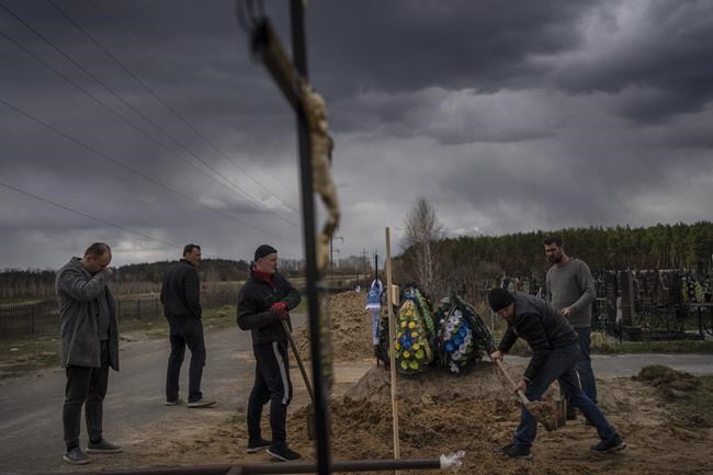Anatoliy Morykin, 45, left, mourns the death of his mother Valentyna Morykina, 82, who died in a retirement home due to poor living conditions during the Russian invasion in Bucha, in the outskirts of Kyiv, Ukraine, Tuesday, April 12, 2022. (AP Photo/Rodrigo Abd)