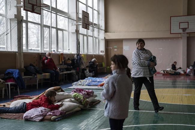 A boy looks at a mobile phone inside a school that is being used as a shelter for people who fled the war, in Dnipro city, Ukraine on Tuesday, April 12, 2022. (AP Photo/Petros Giannakouris)