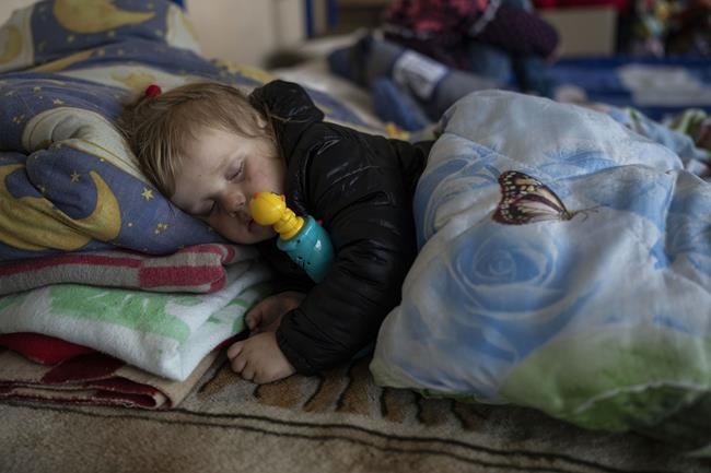 3 year-old Carolina Fedorova sleeps inside a school that is being used as a shelter for people who fled the war, in Dnipro city, Ukraine on Tuesday, April 12, 2022. Carolina fled with her parents and four siblings from the city of Bahmud. (AP Photo/Petros Giannakouris)