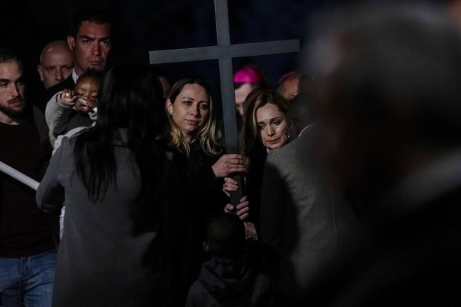 Two nurses from Russia and Ukraine hold the cross as they take part in the Via Crucis (Way of the Cross) torchlight procession presided by Pope Francis on Good Friday in front of Rome's Colosseum, in Rome, Friday, April 15, 2022. (AP Photo/Gregorio Borgia)
