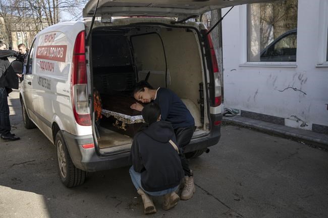 Oksana Kolesnikova embraces the coffin of her son Anatoliy Kolesnikov, 30, a territorial defense soldier who was killed by Russian soldiers in Irpin, in the outskirts of Kyiv, Ukraine, Friday , April 15, 2022. (AP Photo/Rodrigo Abd)