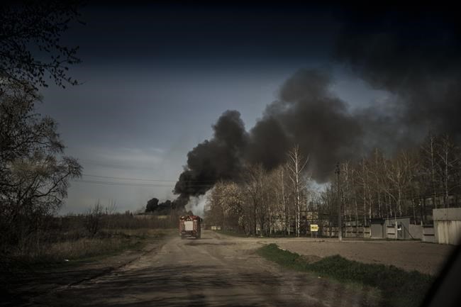 Firefighters drive towards a fire at a factory after a Russian attack in the outskirts of Kharkiv, Ukraine, Friday, April 15, 2022. (AP Photo/Felipe Dana)