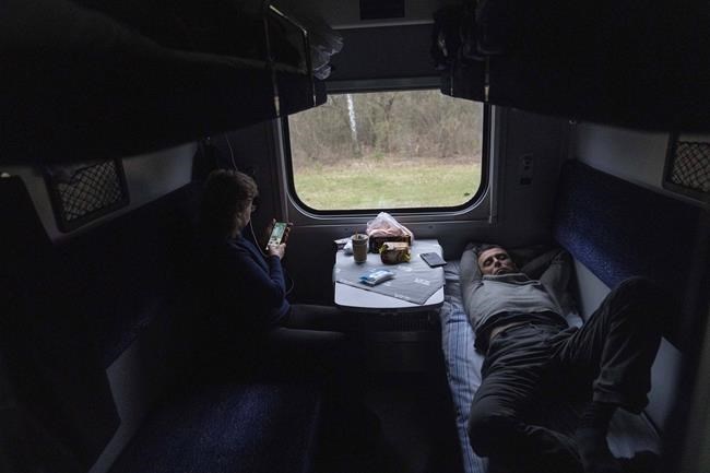 Passengers rest in the train minutes before arriving in Lviv from Kyiv, Ukraine, Sunday, April 17, 2022. (AP Photo/Rodrigo Abd)