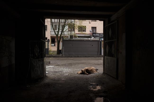 The body of a woman killed a Russian bombardment lies on a sidewalk in downtown Kharkiv, Ukraine, Sunday, April 17, 2022. (AP Photo/Felipe Dana)