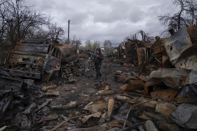A man carries bicycle along a street filled with destroyed Russian military vehicles near Chernihiv, Ukraine, Sunday, April 17, 2022. Witnesses said multiple explosions believed to be caused by missiles struck the western Ukrainian city of Lviv early Monday as the country was bracing for an all-out Russian assault in the east. (AP Photo/Evgeniy Maloletka)
