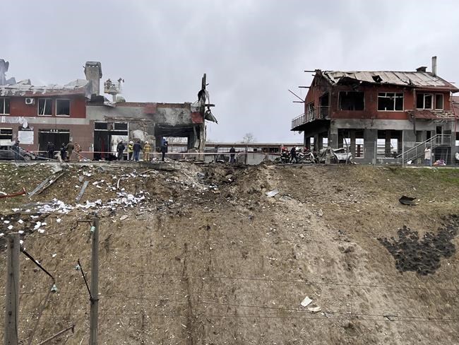 Emergency workers clear up debris after an airstrike hit a tire shop in the western city of Lviv, Ukraine, Monday April 18, 2022. Russian missiles hit the city of Lviv in western Ukraine on Monday, killing at least six people, Ukrainian officials said, as Moscow’s troops stepped up strikes on infrastructure in preparation for an all-out assault on the east. (AP Photo/Philip Crowther)