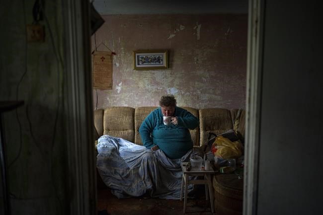 Valentyna Volynets, 59, drinks tea made by her neighbour on a makeshift fire in a public garden near their building in Bucha, on the outskirts of Kyiv, on Monday, April 18, 2022. Citizens of Bucha are still without electricity, water and gas after more than 43 days since the Russian invasion began. (AP Photo/Emilio Morenatti)