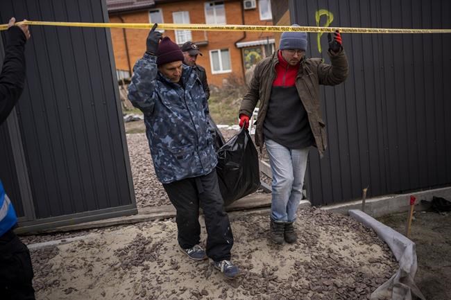 Volunteers carry the body of a civilian killed by the Russian Army in Bucha, to be taken to a morgue for investigation on Monday, April 18, 2022. (AP Photo/Emilio Morenatti)