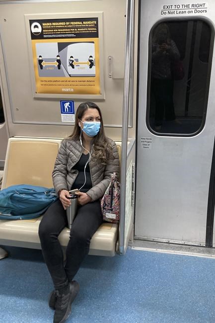 A woman sits on a moving MARTA train with her mask on, Tuesday, April 19, 2022, in Atlanta. (AP Photo/Janelle Cogan)