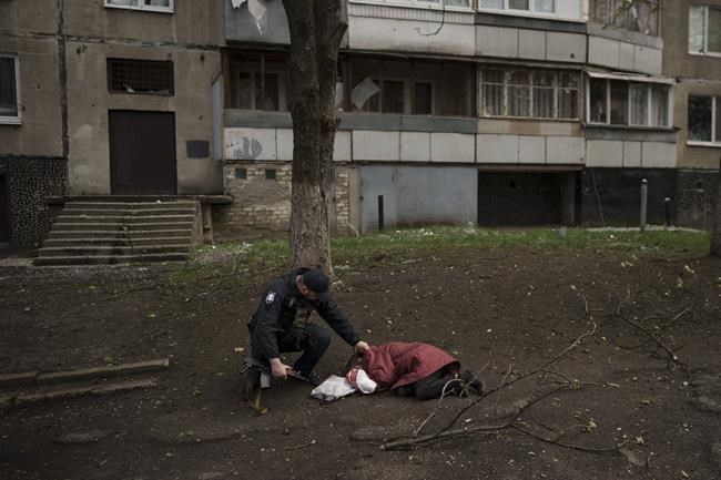 A police officer checks the body of a woman killed during a Russian bombardment at a residential neighborhood in Kharkiv, Ukraine, Tuesday, April 19, 2022. Russia ratcheted up its battle for control of Ukraine’s eastern industrial heartland on Tuesday, intensifying assaults on cities and towns along a front hundreds of miles long in what officials on both sides described as a new phase of the war. (AP Photo/Felipe Dana)
