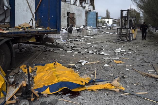 The body of a man is covered by a tarp from a damaged truck following a Russian bombing of a factory in Kramatorsk, in eastern Ukraine, on Tuesday, April 19, 2022. Russian forces attacked along a broad front in eastern Ukraine on Tuesday as part of a full-scale ground offensive to take control of the country's eastern industrial heartland in what Ukrainian officials called a
