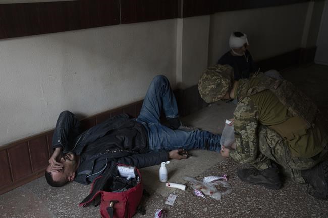 A member of security forces gives first aid to an injured man following a Russian bombing of a factory in Kramatorsk, eastern Ukraine, Tuesday, April 19, 2022, killing at least one person and injuring three others. Russian forces attacked along a broad front in eastern Ukraine on Tuesday as part of a full-scale ground offensive to take control of the country's eastern industrial heartland in what Ukrainian officials called a