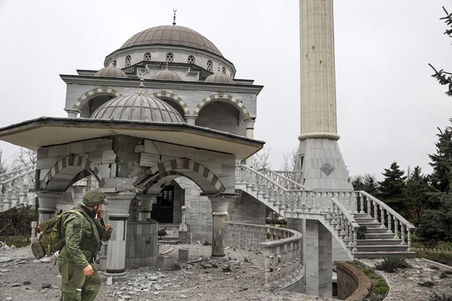 A serviceman of Donetsk People's Republic militia walks past damaged during a heavy fighting mosque in an area controlled by Russian-backed separatist forces in Mariupol, Ukraine, Tuesday, April 19, 2022. Taking Mariupol would deprive Ukraine of a vital port and complete a land bridge between Russia and the Crimean Peninsula, seized from Ukraine from 2014. (AP Photo/Alexei Alexandrov)
