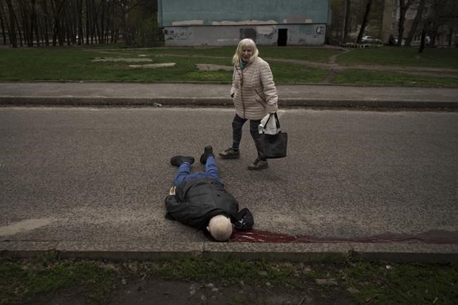 A woman walks next to the body of a man killed during a Russian bombardment at a residential neighborhood in Kharkiv, Ukraine, Tuesday, April 19, 2022. Russia ratcheted up its battle for control of Ukraine’s eastern industrial heartland on Tuesday, intensifying assaults on cities and towns along a front hundreds of miles long in what officials on both sides described as a new phase of the war. (AP Photo/Felipe Dana)