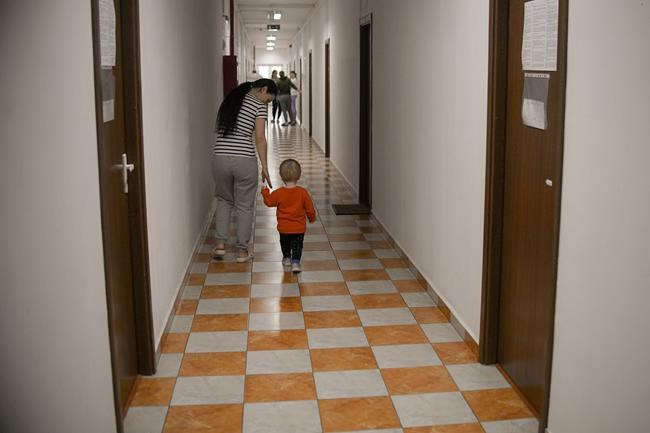 A woman walks with a child on the hallway of a refugee center in Bucharest, Romania, Tuesday, April 19, 2022. The United Nations’ refugee agency says that more than 5 million people have now fled Ukraine since the Russian invasion began on Feb. 24. The Geneva-based U.N. High Commissioner for Refugees on Wednesday, April 20, 2022 put the total number of refugees at 5.01 million. (AP Photo/Andreea Alexandru)