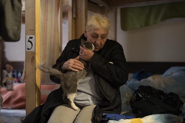 Alexandra Kusminova pets her cat, named Mouse, as she sits on a bed settled in a restaurant that was transformed into a shelter for those who are fleeing the war from the eastern region of the country in Dnipro, Ukraine, Wednesday, April 20, 2022.