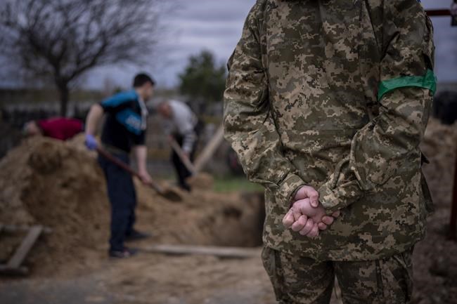 A Ukrainian soldier stands during the funeral of his father, who died due to the lack of medical care because of the Russian occupation, in Bucha, on the outskirts of Kyiv, on Wednesday, April 20, 2022. (AP Photo/Emilio Morenatti)